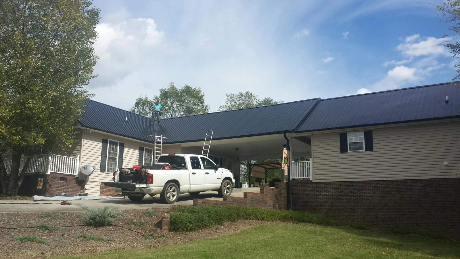Black metal roof over a home and attached breezeway with ladders set in Montpelier